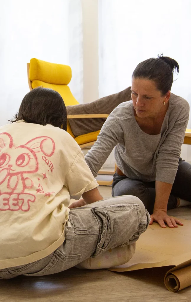 Dr. Julia Meyer-Lückel im Gespräch mit Kind auf dem Boden sitzend, Rapportaufbau