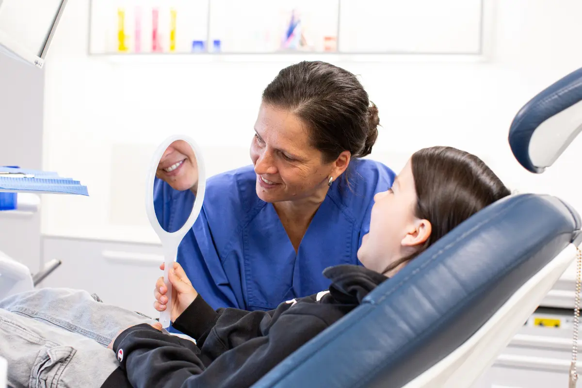 Kind sitzt entspannt im Zahnarztstuhl während einer kinderzahnmedizinischen Behandlung