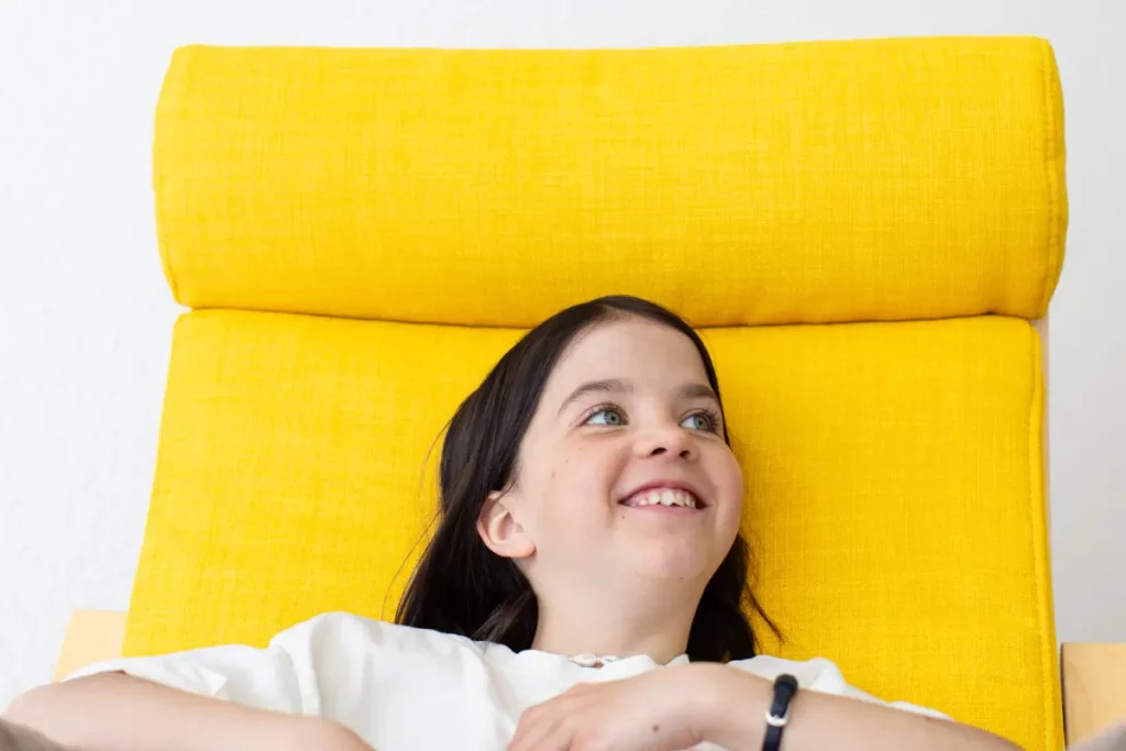 fröhliches Kind liegt ruhig in einem Sessel während einer Hypnosesitzung